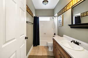 Full bathroom featuring shower / tub combo with curtain, vanity, and light tile patterned floors