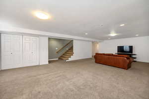 Unfurnished living room with light colored carpet and stairway