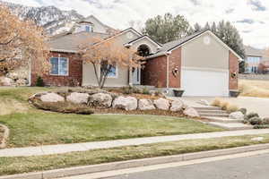 View of front facade featuring brick siding, concrete driveway, a front lawn, an attached garage, and roof with shingles