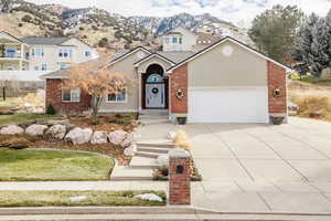 Traditional-style house with driveway, a mountain view, stucco siding, brick siding, and an attached garage