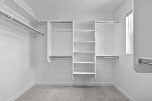 Spacious closet featuring light colored carpet