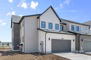 View of front facade with a garage, driveway, and roof with shingles
