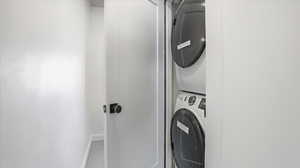 Washroom with estacked washer and dryer and carpet flooring