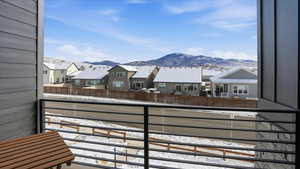 Snow covered back of property with a mountain view and a residential view