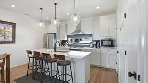 Kitchen featuring white cabinets, backsplash, a breakfast bar area, and recessed lighting