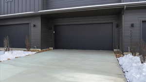 Snow covered garage featuring driveway