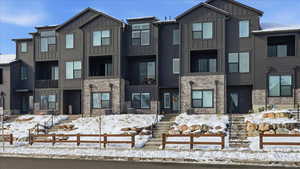 View of front facade featuring board and batten siding, stone siding, and a balcony