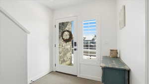 Doorway featuring baseboards and carpet