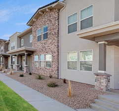 View of front of home with a porch, stucco siding, and stone siding