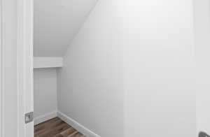 Spacious closet with dark wood-style floors and vaulted ceiling