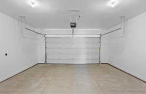 Garage with baseboards and a garage door opener