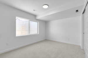 Empty room with light colored carpet and baseboards