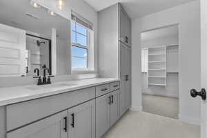 Full bath featuring a stall shower, vanity, a walk in closet, and light tile patterned floors