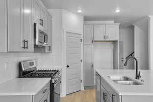 Kitchen with appliances with stainless steel finishes, light wood-style flooring, decorative backsplash, light stone countertops, and recessed lighting