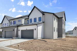 Modern inspired farmhouse with concrete driveway, an attached garage, and roof with shingles