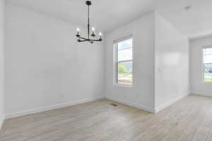 Spare room with light wood-type flooring and a chandelier