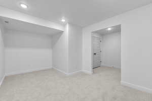 Additional living space with light carpet and recessed lighting