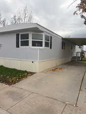 View of property exterior featuring concrete driveway and a carport
