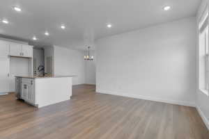 Kitchen featuring white cabinetry, a center island with sink, recessed lighting, a chandelier, and light wood-style floors