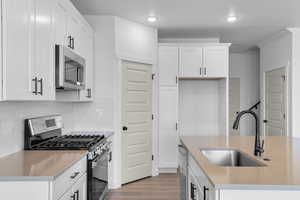 Kitchen featuring appliances with stainless steel finishes, light stone countertops, white cabinetry, and recessed lighting