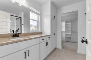 Full bath featuring a stall shower, vanity, light tile patterned floors, and a spacious closet