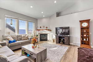 Main floor family featuring vaulted ceiling, a glass covered fireplace, and recessed lighting