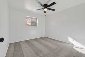 Carpeted bedroom with a ceiling fan and baseboards