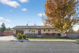 Single story home featuring stucco siding, stone siding, an attached garage, and driveway