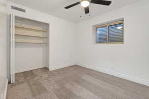 Unfurnished bedroom featuring light carpet, crown molding, a ceiling fan, and a closet