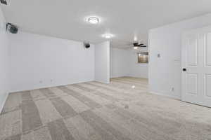 Family room with a textured ceiling, light colored carpet, and ceiling fan