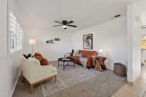 Living area featuring plantation shutters, carpet floors and ceiling fan