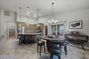 Dining space featuring a high ceiling, arched walkways, a chandelier, and recessed lighting
