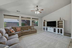 Living room featuring carpet flooring, lofted ceiling, and ceiling fan