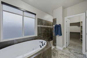 Bathroom with a tub with jets, a spacious closet, and a walk in shower