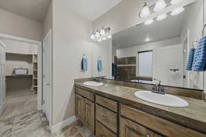 Full bath featuring double vanity and a walk in closet