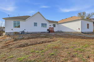Back of house featuring a patio, a lawn, and a shingled roof