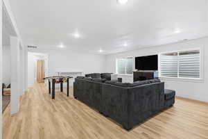 Living area with light wood-type flooring and recessed lighting