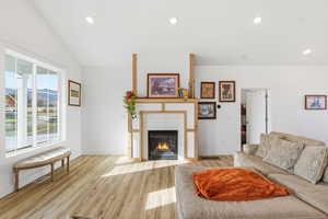 Living area featuring a fireplace, light wood finished floors, recessed lighting, and vaulted ceiling