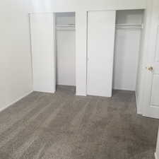 Unfurnished bedroom with multiple closets and dark carpet