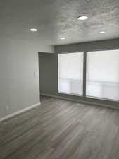 Empty room with a textured ceiling, recessed lighting, and light wood finished floors