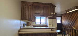 Kitchen with a peninsula, stainless steel stove, light countertops, dark brown cabinetry, and a textured ceiling