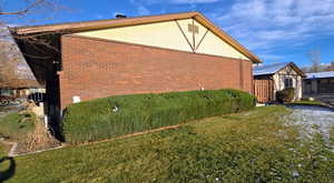 View of home's End unit side view featuring brick siding and a lawn