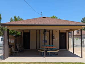 Covered patio structure featuring a shingle roof, beige siding, and dark trim