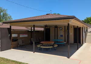 Covered patio area featuring a brown shingle roof, beige siding, and dark support pillars