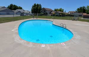 Curved swimming pool with light blue water surrounded by a concrete deck