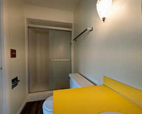 Full bathroom with a shower stall and dark wood-style floors