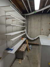 Utility area featuring concrete walls, exposed ceiling joists, white adjustable shelving, a fluorescent light fixture, and visible ductwork