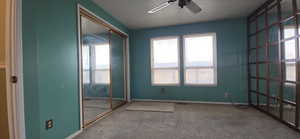 Carpeted empty room with ceiling fan and baseboards