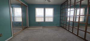 Carpeted spare room featuring ceiling fan and baseboards