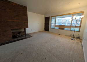 Unfurnished living room featuring a textured ceiling, a fireplace, and carpet flooring